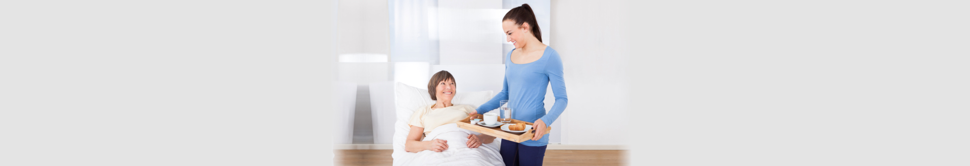 Female caregiver serving breakfast to senior woman at nursing home